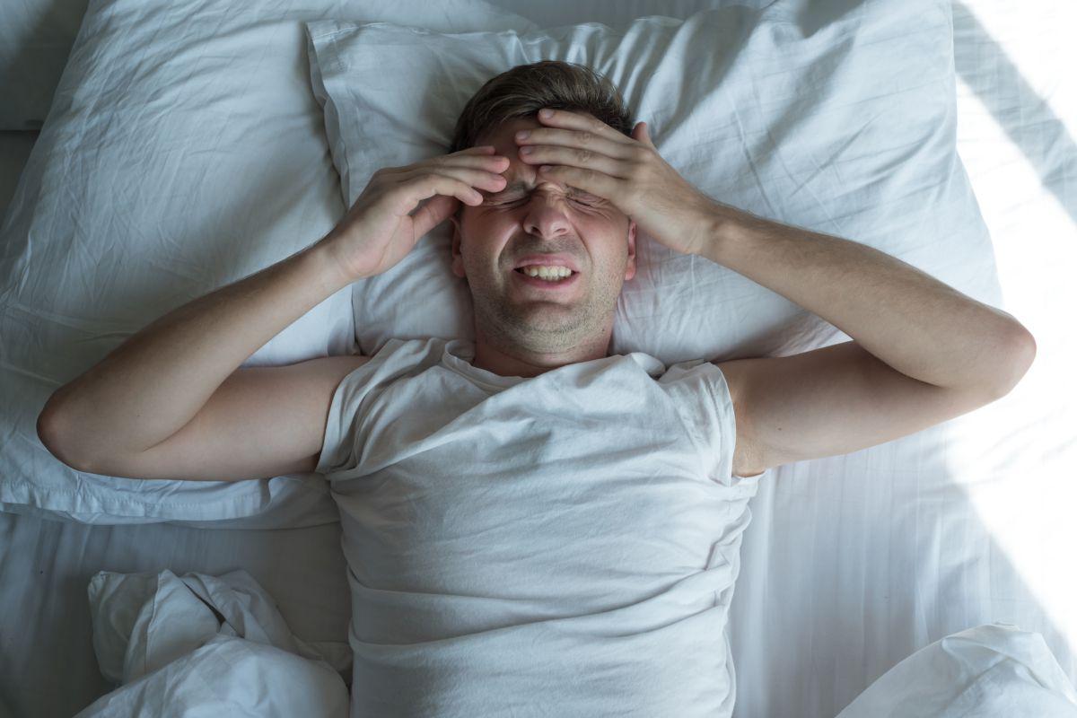 Pan na łóżku mający migrene przed snem